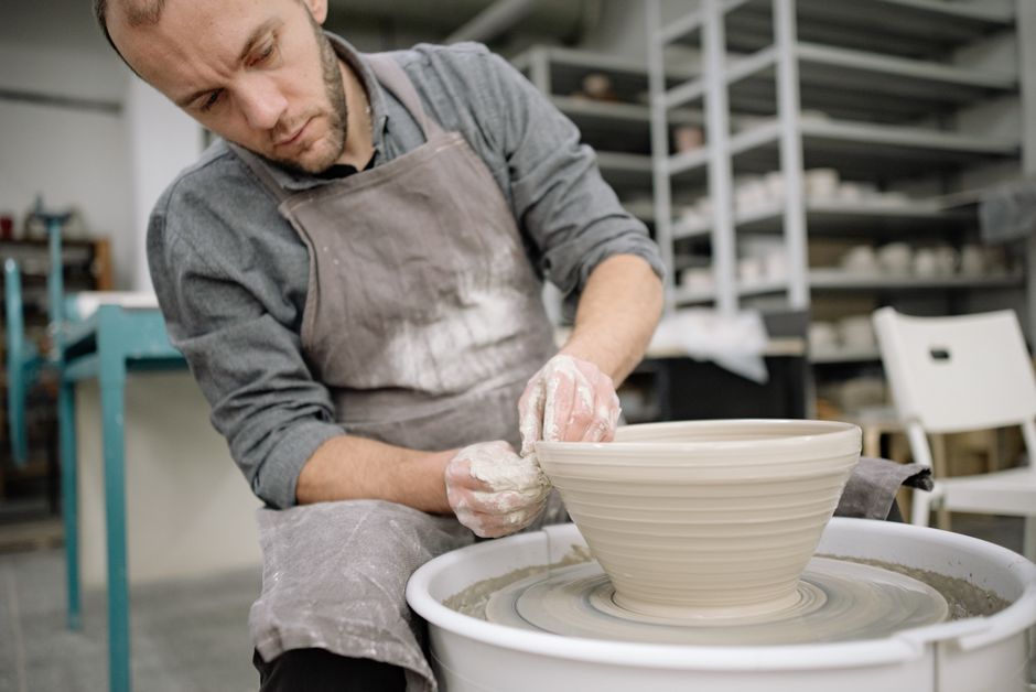 Potter skillfully shaping a clay bowl on a pottery wheel in a workshop.