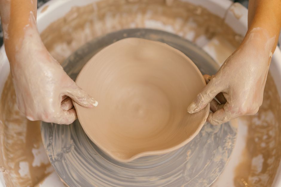 Close-up of hands shaping a ceramic bowl on a pottery wheel, showcasing craftsmanship.