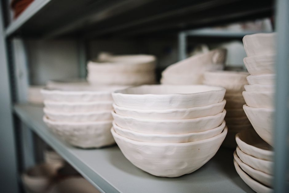 Close-up of stacked handmade ceramic bowls on a storage shelf.