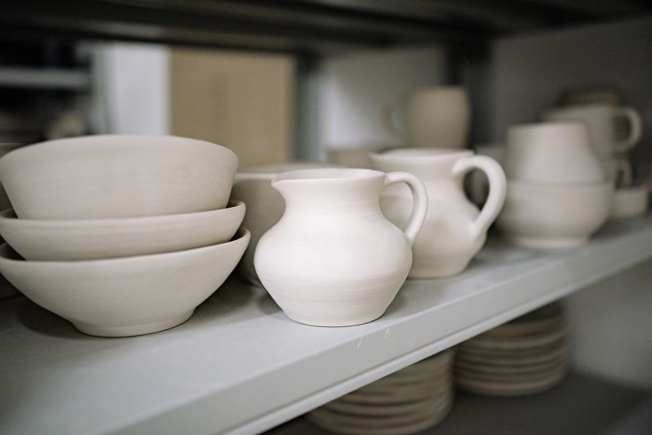 Close-up of handmade pottery bowls and jugs on a workshop shelf, showcasing artisanal craftsmanship.